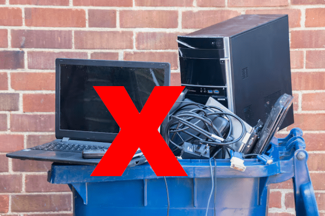 Computers in a recycling bin with a large red ex in front.